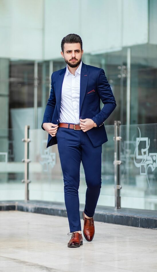 man in blue suit standing on sidewalk during daytime